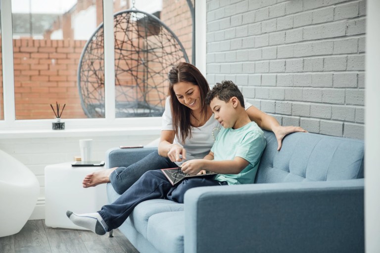 Woman and boy sitting together on a sofa looking at a tablet