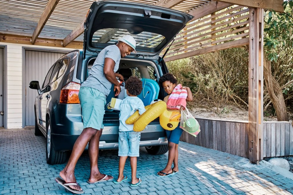 Man and two children loading beach gear into the boot of an SUV