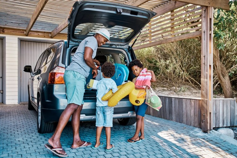 Man and two children loading beach gear into the boot of an SUV